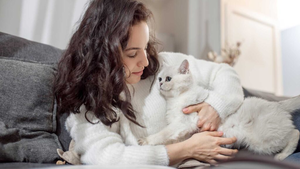 Female pet owner looking happy while spending time with her cat.